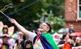 Person making bubbles with rainbow flag tied round them