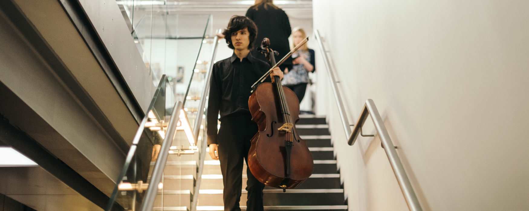 Man walking down stairs with a string instrument