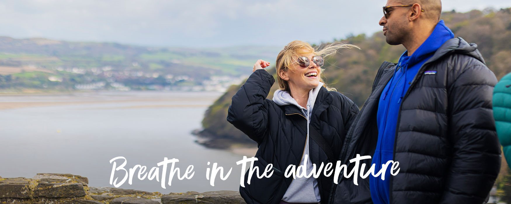 Couple overlooking the sea with sunglasses on in Wales