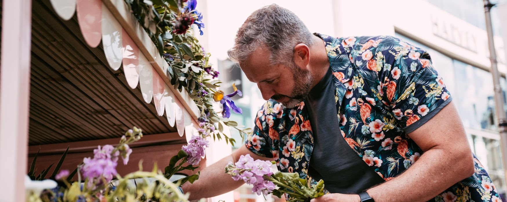 Man placing flowers in a floral display