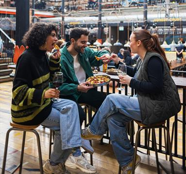riends eating food at a tabel in Mackie Mayor, Manchester