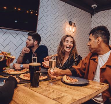 Group sat inside O'Neills bar, drinking and eating pizza