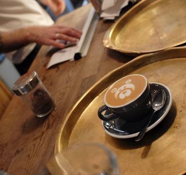 Coffee in a cup and saucer with teddy bear coffee art.