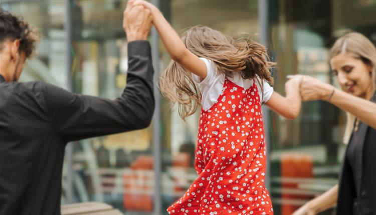 A child in a red dress with their parents
