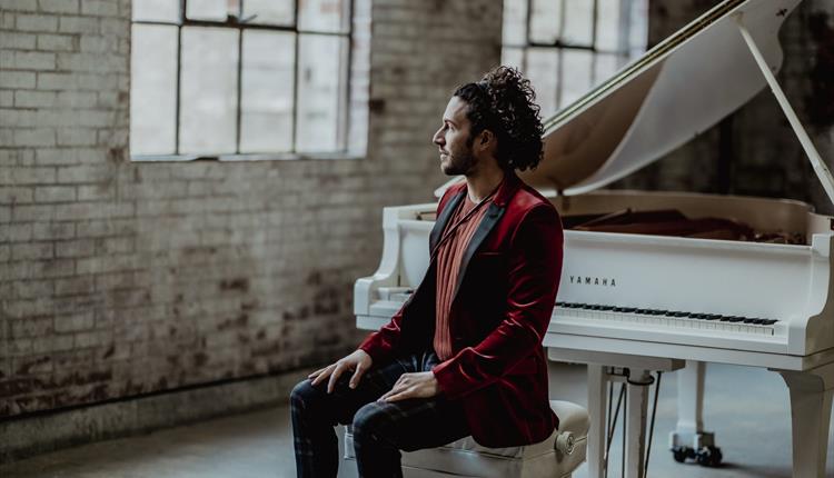 Performer sat at a white grand piano