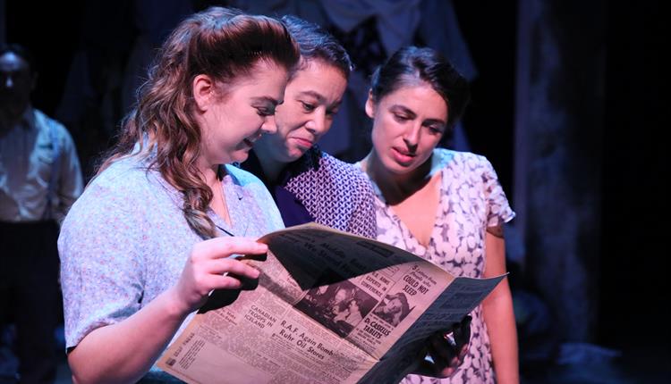 Three girls reading newspaper