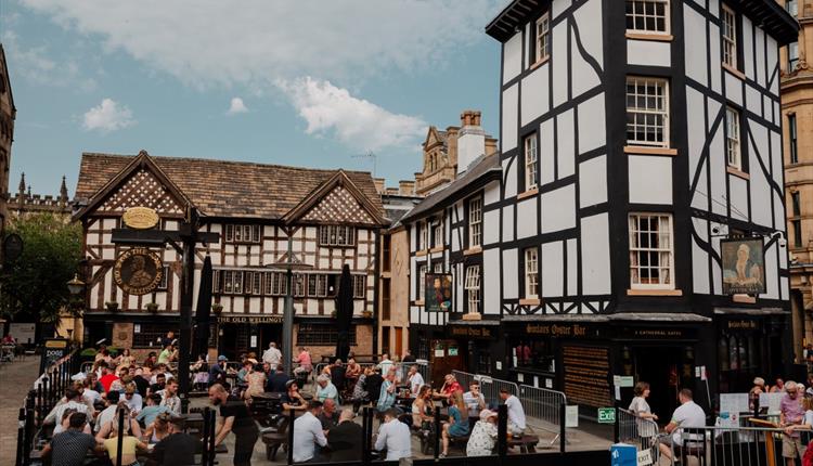 People sat in a square outside Tudor building