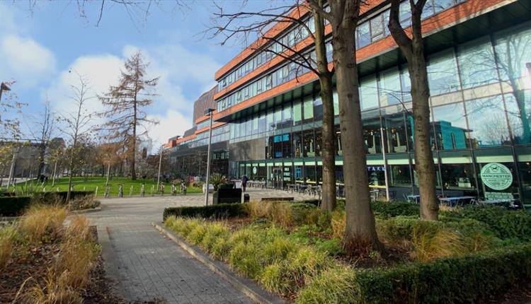 University Green with shops and trees, view from Oxford Road