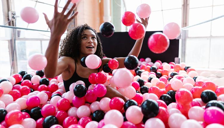 Woman Sitting in a Ball Pit Pool and Throwing Plastic Balls 
