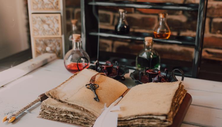 An Old Book and Candles on Wooden Table with Glass Bottles
