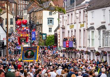 Crowds pass under the balcony of the County Hotel and along Old Elvet at the 2019 Durham Miners' Gala