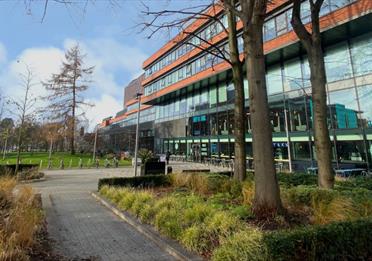 University Green with shops and trees, view from Oxford Road