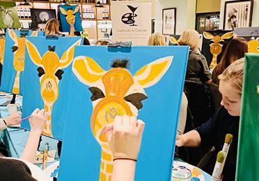 Guests painting a giraffe at Cocktails n Canvas event