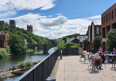 A view of the river and shoppers sat outside for refreshments.