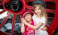 2 children holding hands in front of a large wheel