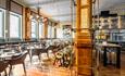 The Refuge Restaurant Area inside Kimpton Clocktower Hotel. Chairs and tabes set up
