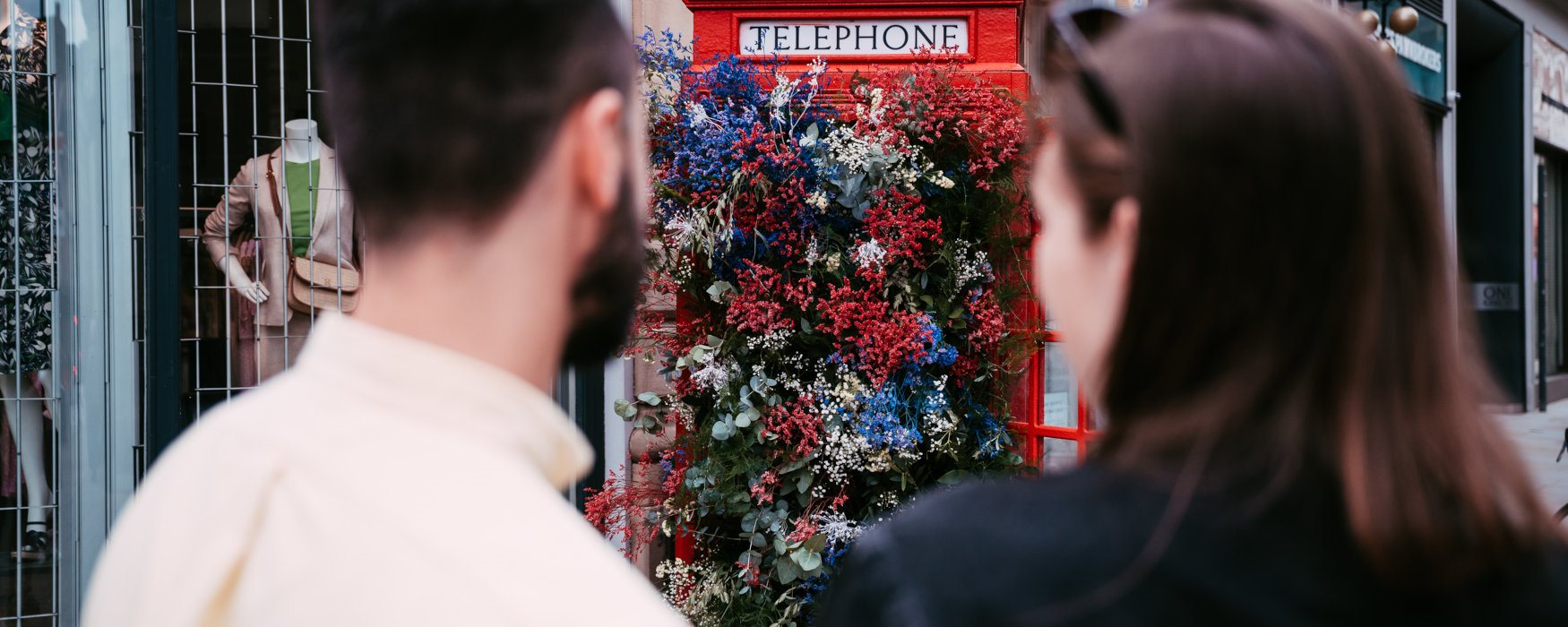 2 people looking at a floral telephone box in Manchester