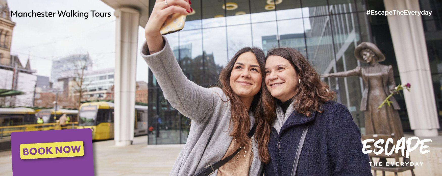 2 people taking a selfie in front of the Pankhurst statue in Manchester