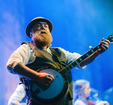 Man playing banjo on stage at Fairytale of New York