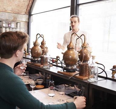Man explaining the gin-making process to two people at Manchester Gin