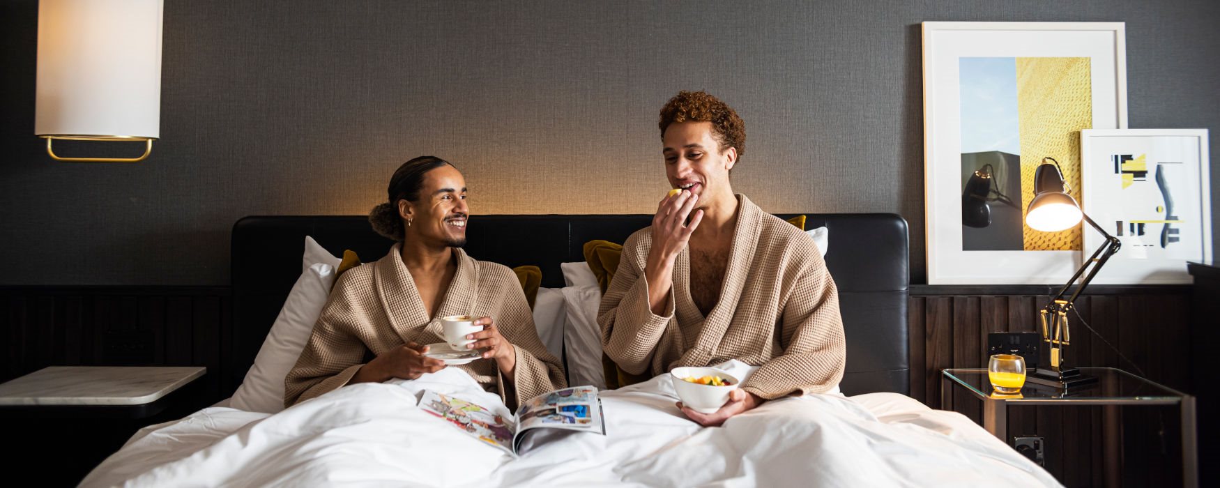 Couple in bed with breakfast at hotel in Manchester