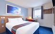 Example of a room inside Rochdale Travelodge, with a double bed, desk and lamp.
