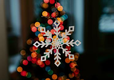 White wooden snowflake decoration lit up by multi-coloured lights
