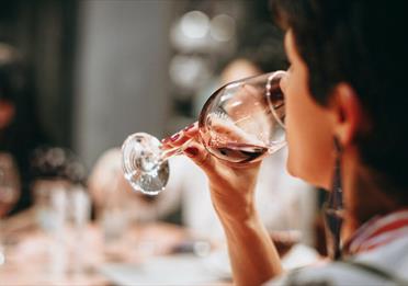 A person drinking from a clear wine glass