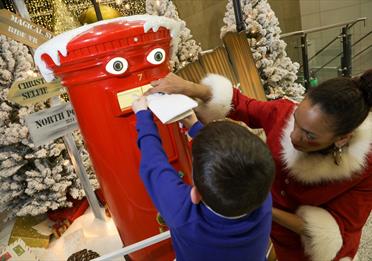 Christmas at Manchester Arndale, child adding a letter to a postbox