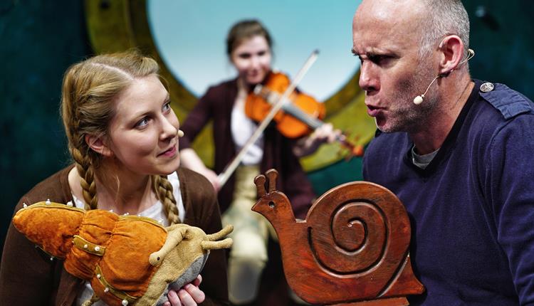 The Snail and the Whale: Two actors on stage holding snail toys