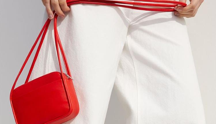 Woman in white holding a red handbag