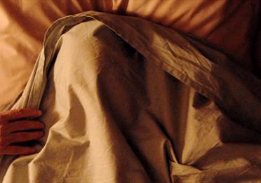 Person in bed, hiding under the sheets