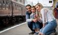 Family with small child pointing at a train on a train platform