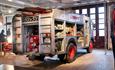 A vintage fire engine with equipment compartments open for display.