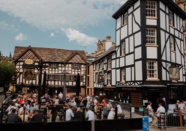 People sat in a square outside Tudor building