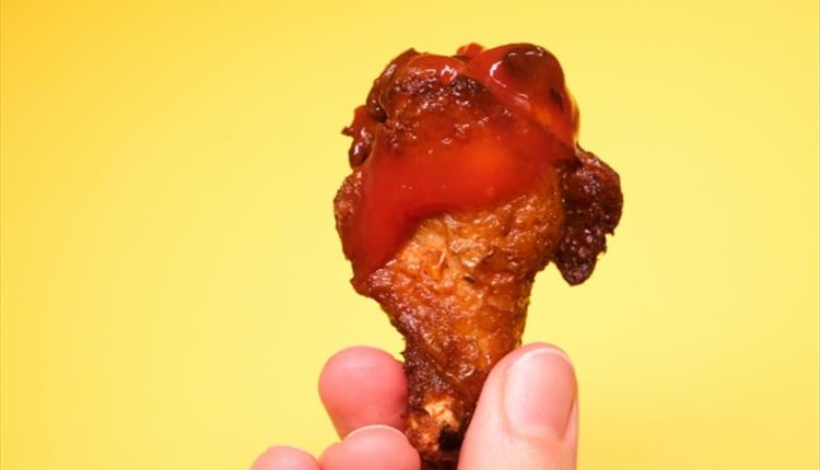 Anonymous person demonstrating fried chicken with ketchup in hand
