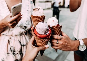 Crop unrecognizable friends clinking ice creams on street
