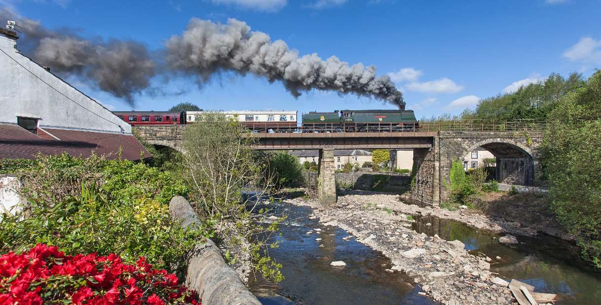East Lancashire Railway train travelling over countryside bridge