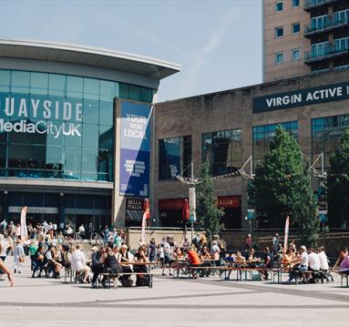 External Quayside MediaCityUK shot in summer with people sat at tables 