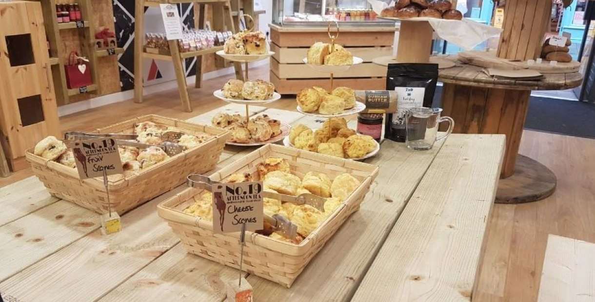 A selection of freshly-made scones in a basket and displayed behind on stands