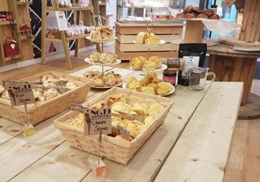 A selection of freshly-made scones in a basket and displayed behind on stands
