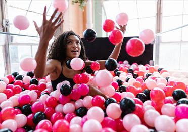 Woman Sitting in a Ball Pit Pool and Throwing Plastic Balls 
