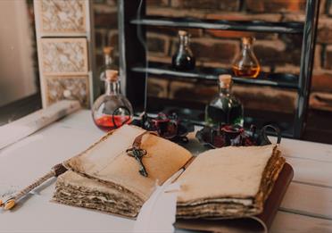 An Old Book and Candles on Wooden Table with Glass Bottles
