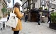 Person with a Manchester Worker Bee bag outside a Tudor building in Manchester
