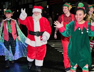 Santa walking with his elves waving