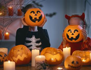 Children in Halloween costume holding pumpkins up