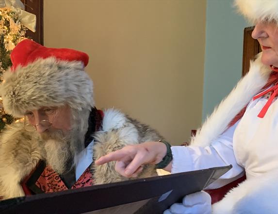 Santa and Mrs Claus reading the naughty and nice lists in Santa's study.