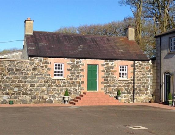 The exterior of a cottage with a green door