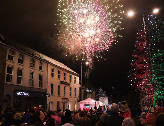 Multi-coloured fireworks are exploding in the sky over the roof of buildings on Magherafelt's Main Street