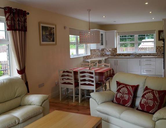 Open plan kitchen, dining and living area with 2 cream 2 seater sofas and dining table with 4 chairs